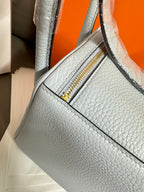 Light blue leather handbag with side zipper opening and gold zipper pull.