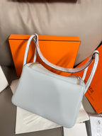 Light blue leather shoulder bag with long strap, front flap, and gold hardware.