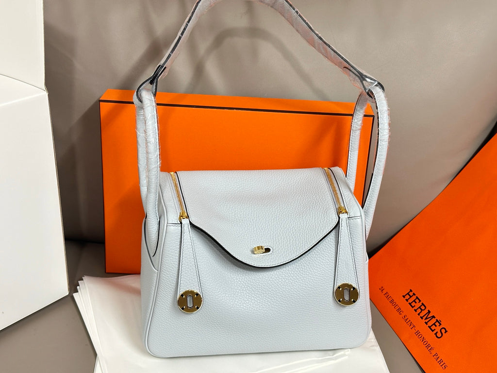 Light blue leather handbag with front flap and gold turn-lock hardware.