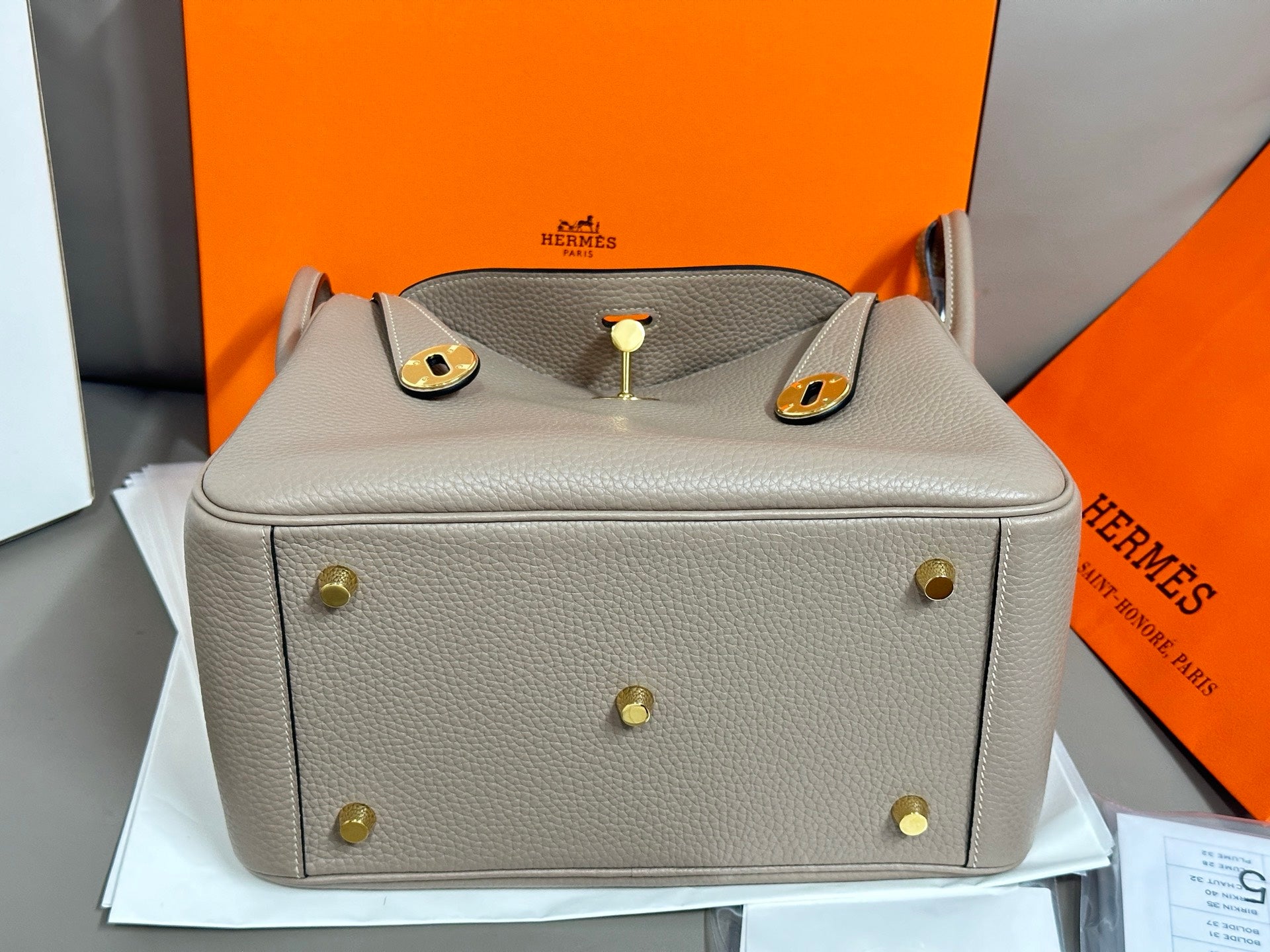Hermes light gray leather handbag front view with gold-tone feet and top flap hardware
