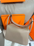 Hermes light gray leather handbag with top handles and textured trim along the edges