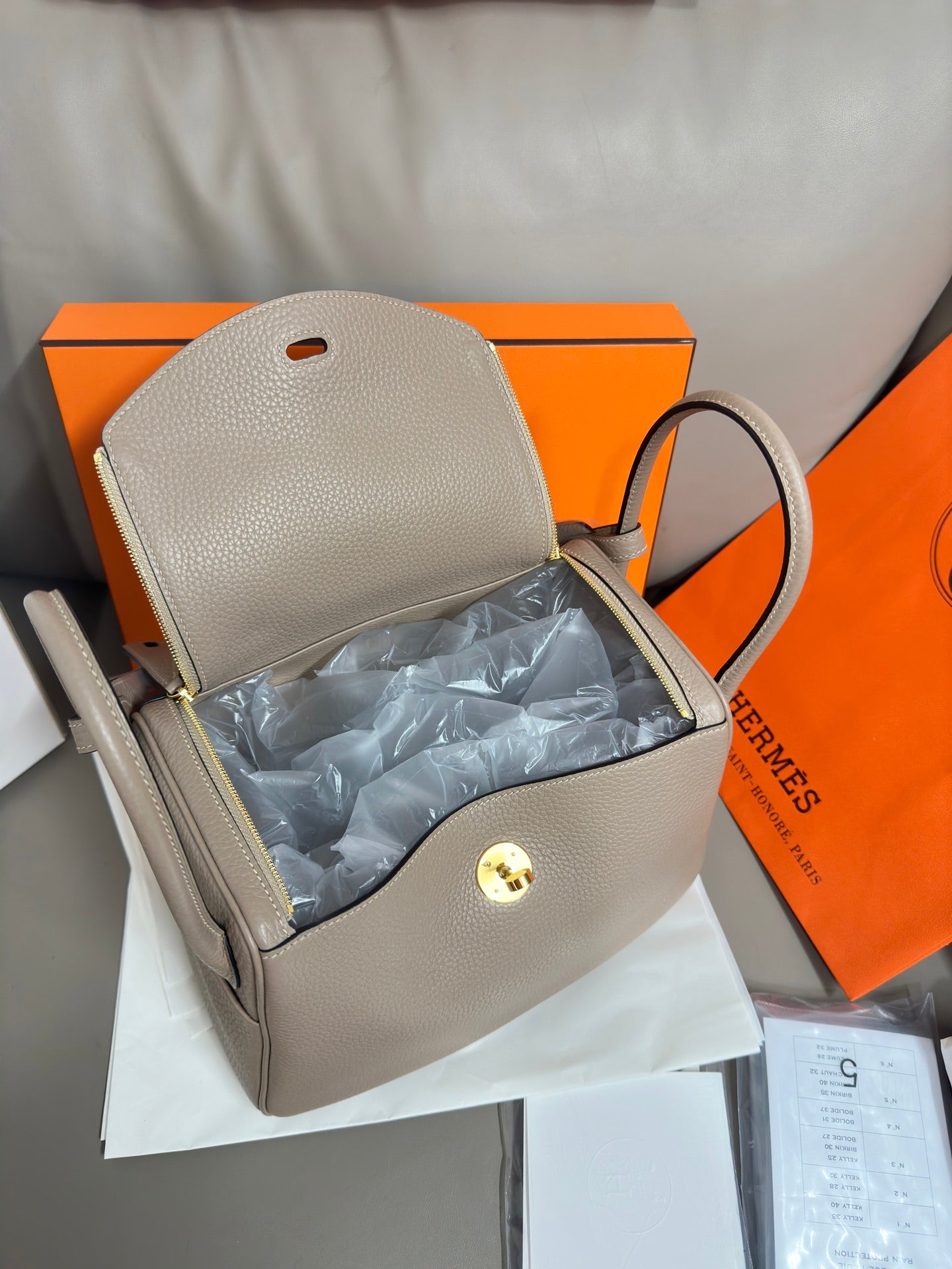 Hermes light gray leather handbag open view with interior lining and front clasp hardware