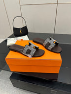 Hermes ladies slide sandals, black with silver rhinestone H buckle, angled view