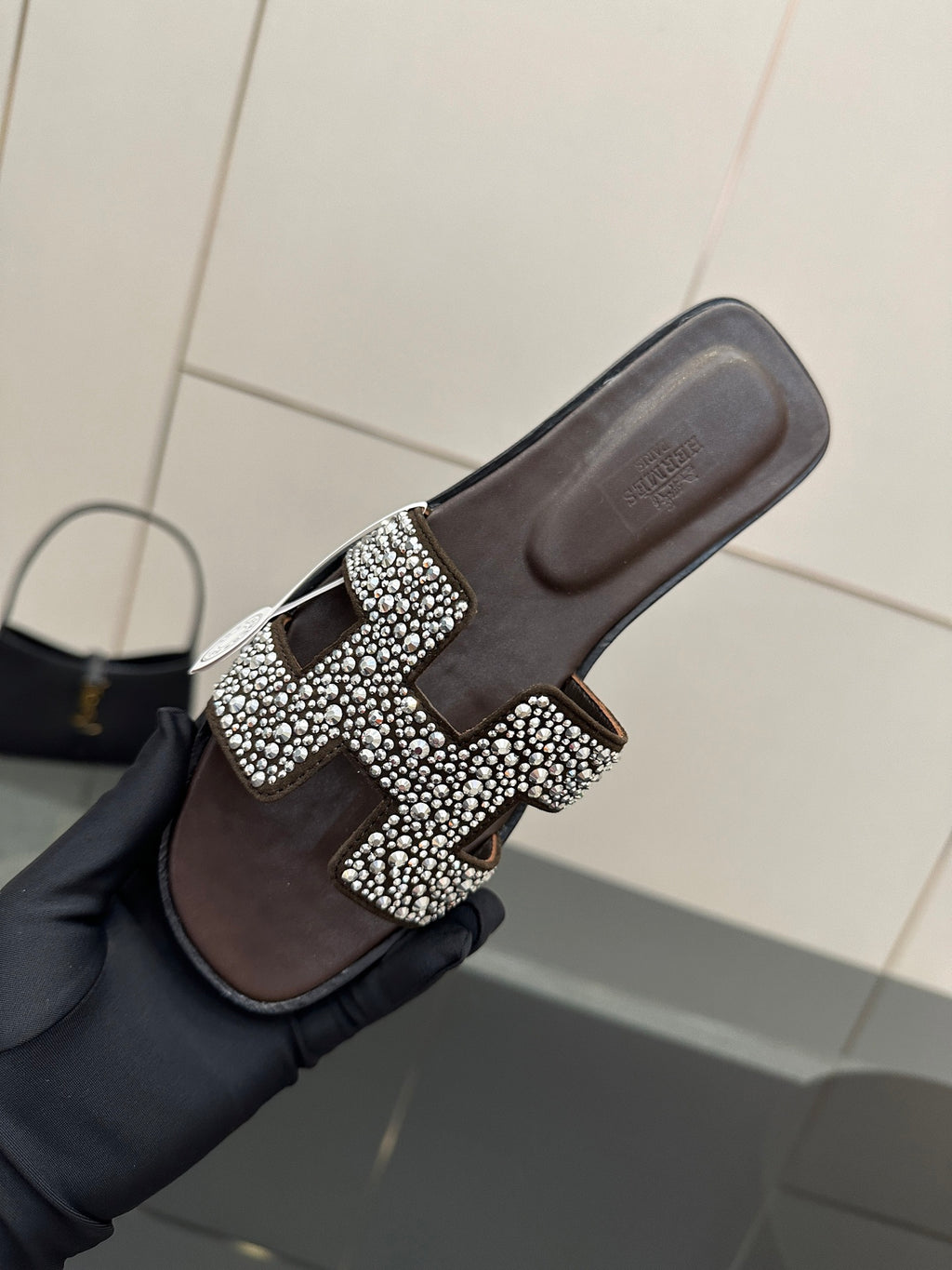 Hermes ladies slide sandal close-up, black with silver rhinestone H buckle on strap