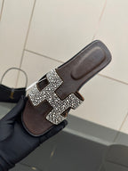Hermes ladies slide sandal close-up, black with silver rhinestone H buckle on strap