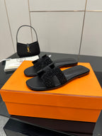 Black slide sandals with rhinestone cross strap, single shoe front view
