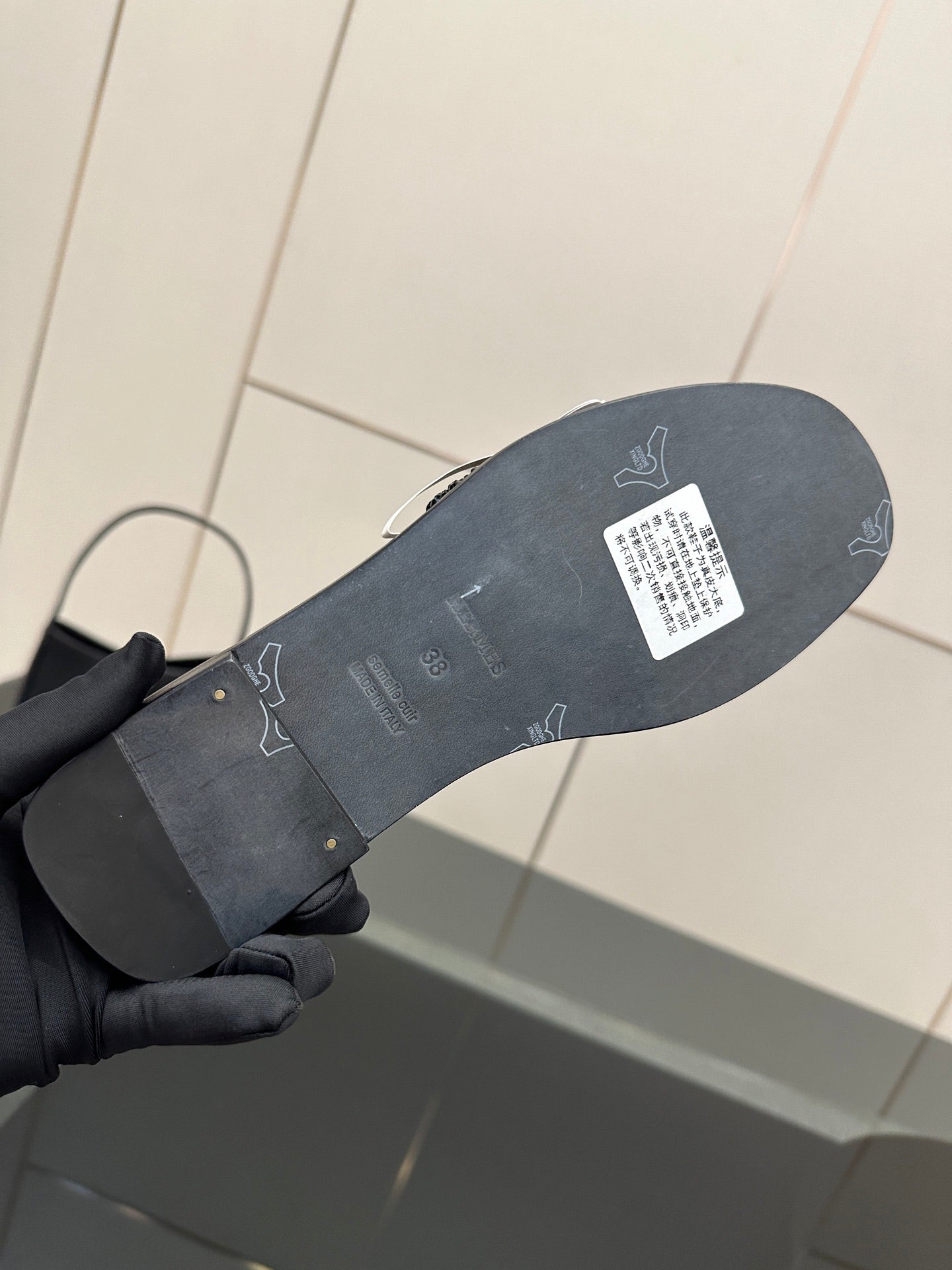 Black slide sandal outsole view in hand, textured tread and label