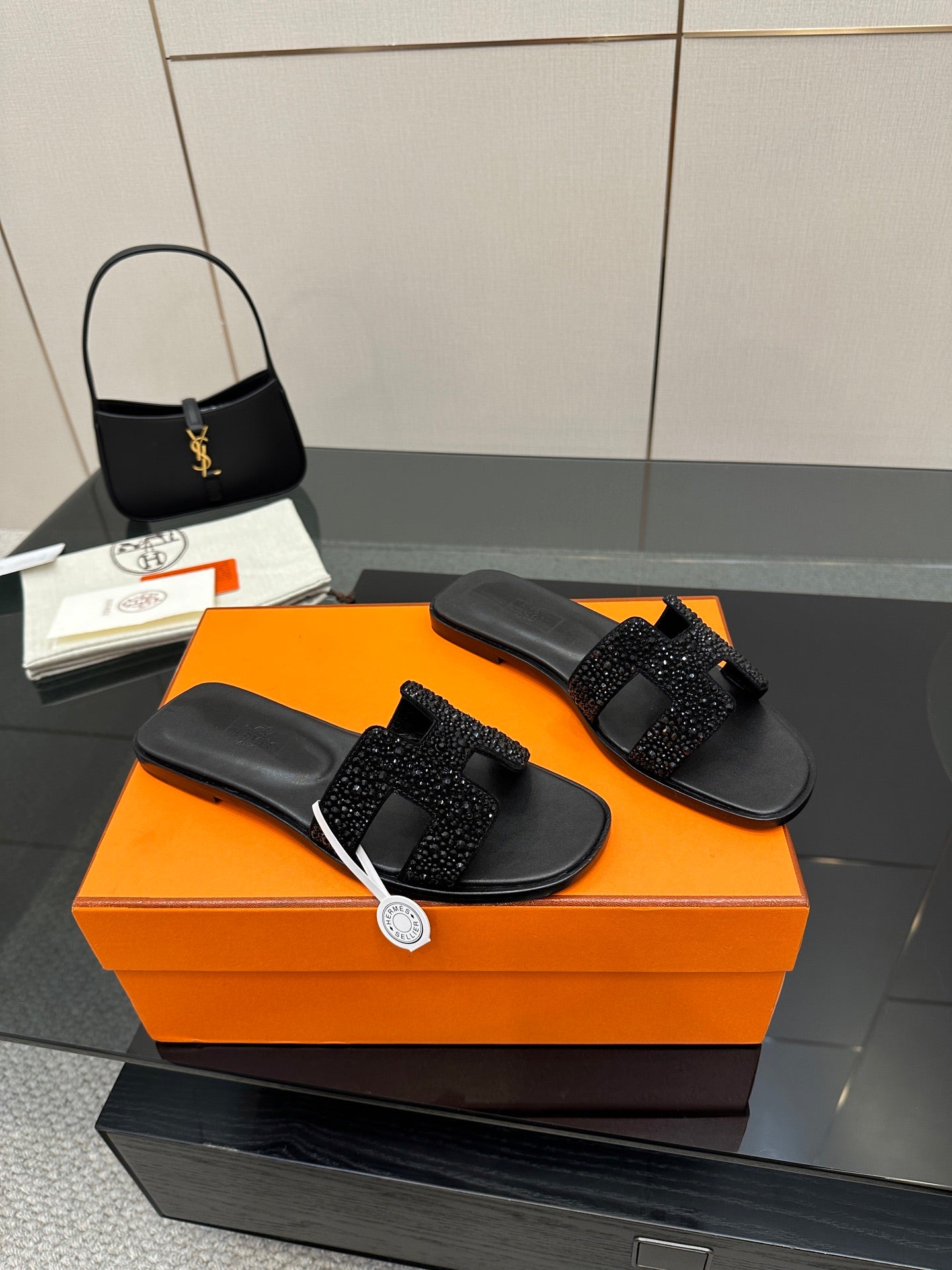 Black slide sandals with rhinestone buckle strap, angled side view
