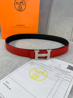Hermes belt with red leather strap and silver-toned H buckle over black inner lining.