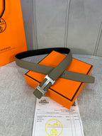 Reversible leather belt with olive strap and silver H buckle, on paperwork