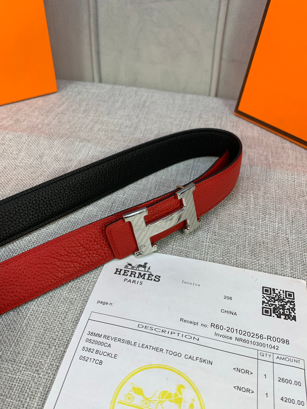 Reversible belt: red face with black reverse, silver H buckle and leather texture.