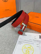 Red and black reversible leather belt with silver buckle, laying across paperwork.