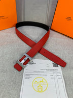 Red leather belt with silver H buckle and black inner side, laid flat with paperwork.