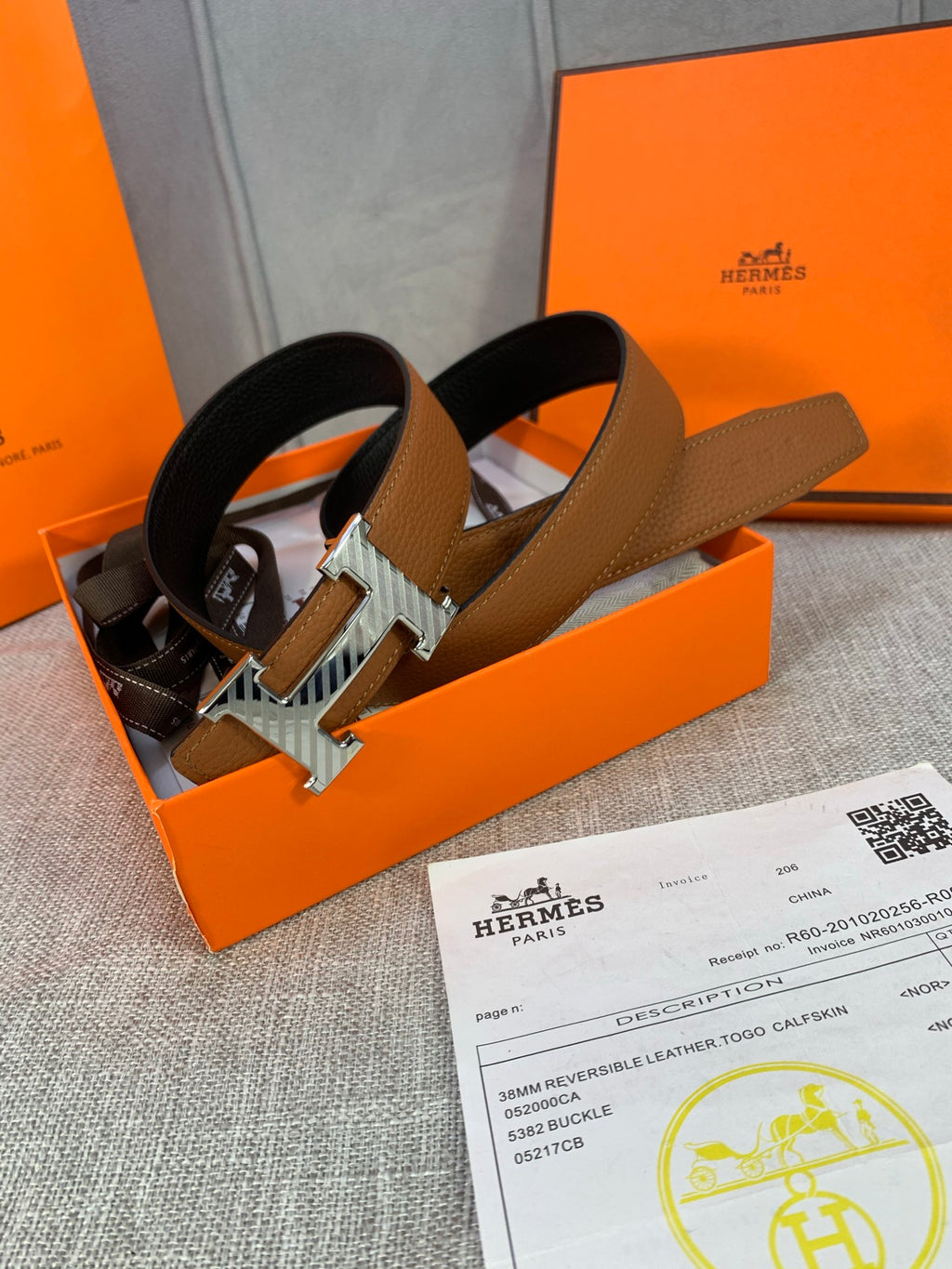 Brown reversible leather belt with silver H buckle, laid in open box
