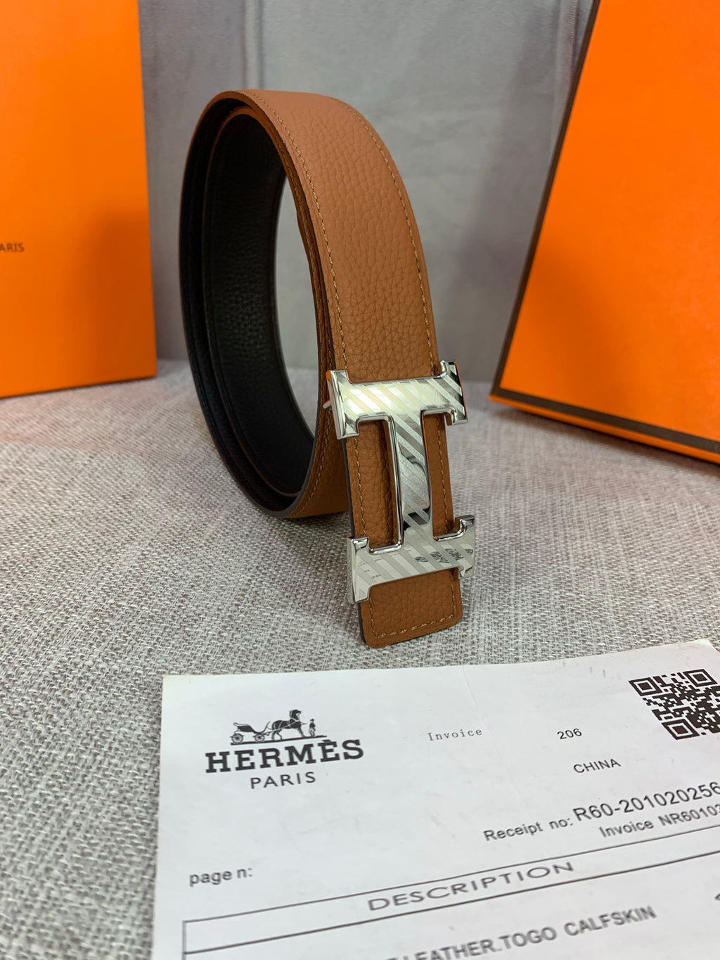 Brown leather belt with silver buckle and leather strap end, side view