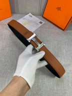 Brown leather belt with black underside and silver H buckle, adjustable loop