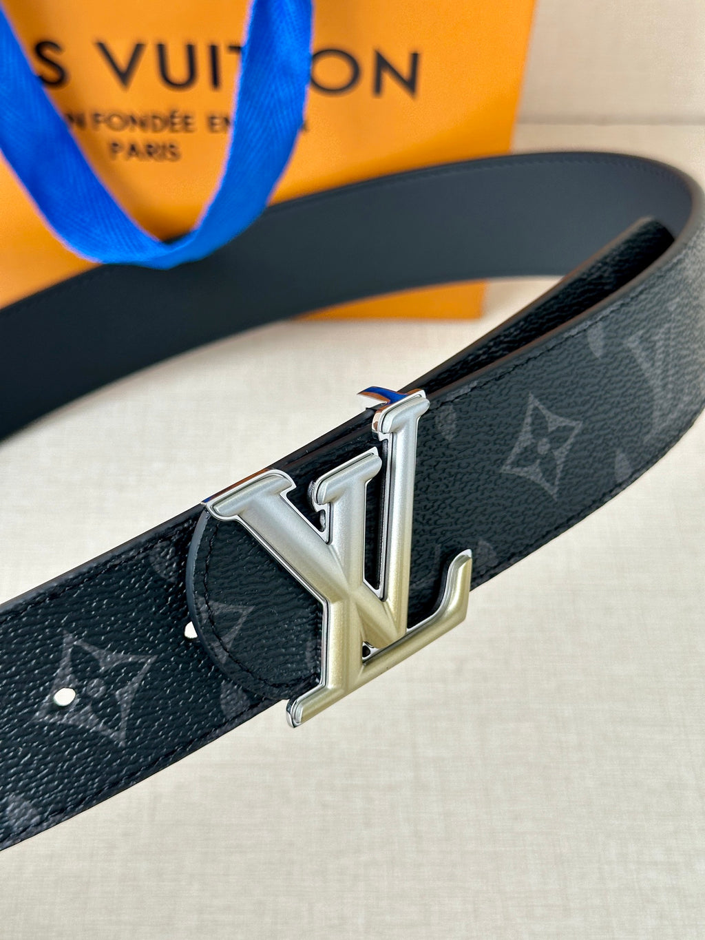 Louis Vuitton belt close-up: dark monogram strap with silver LV buckle