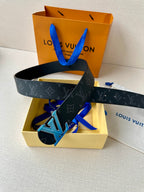 Louis Vuitton monogram belt with dark strap and blue LV buckle, placed in box