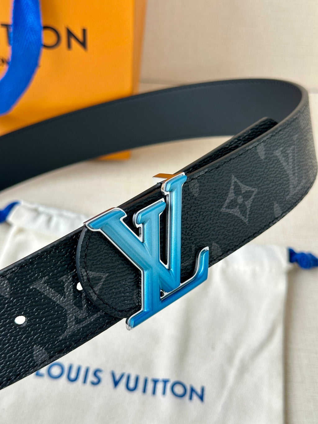 Louis Vuitton belt close-up with dark monogram strap and blue LV buckle detail