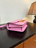 Pink leather handbag with flap front and gold H clasp, side angle