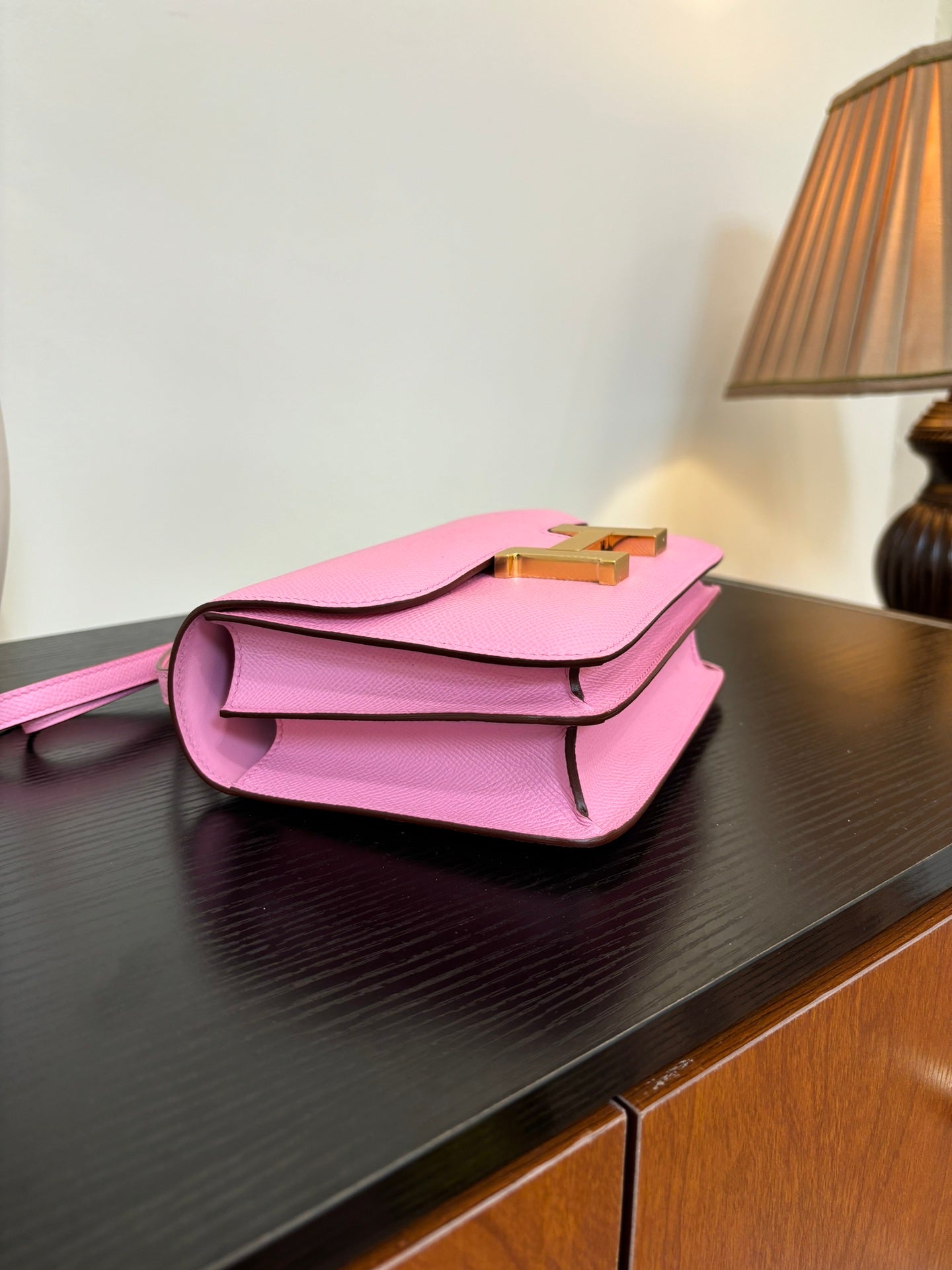 Pink leather handbag with flap front and gold H clasp, side angle