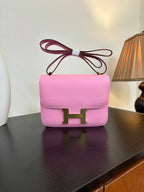 Pink leather handbag with flap front and gold H clasp, bow-tie top handle