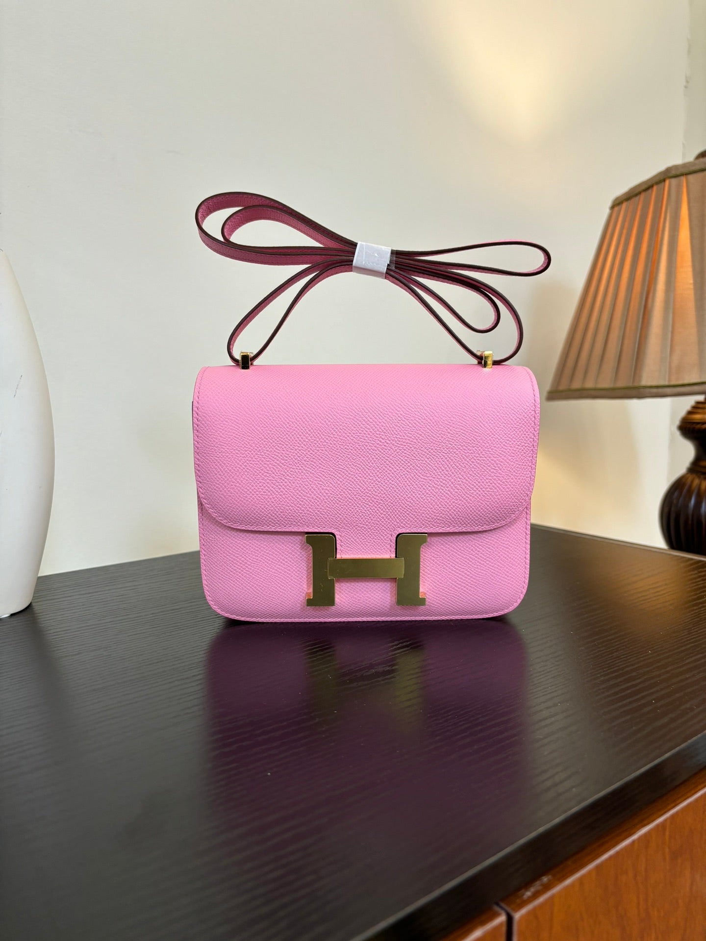 Pink leather handbag with flap front and gold H clasp, bow-tie top handle
