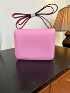 Pink leather handbag with flap front and gold H clasp, front view with tied handle