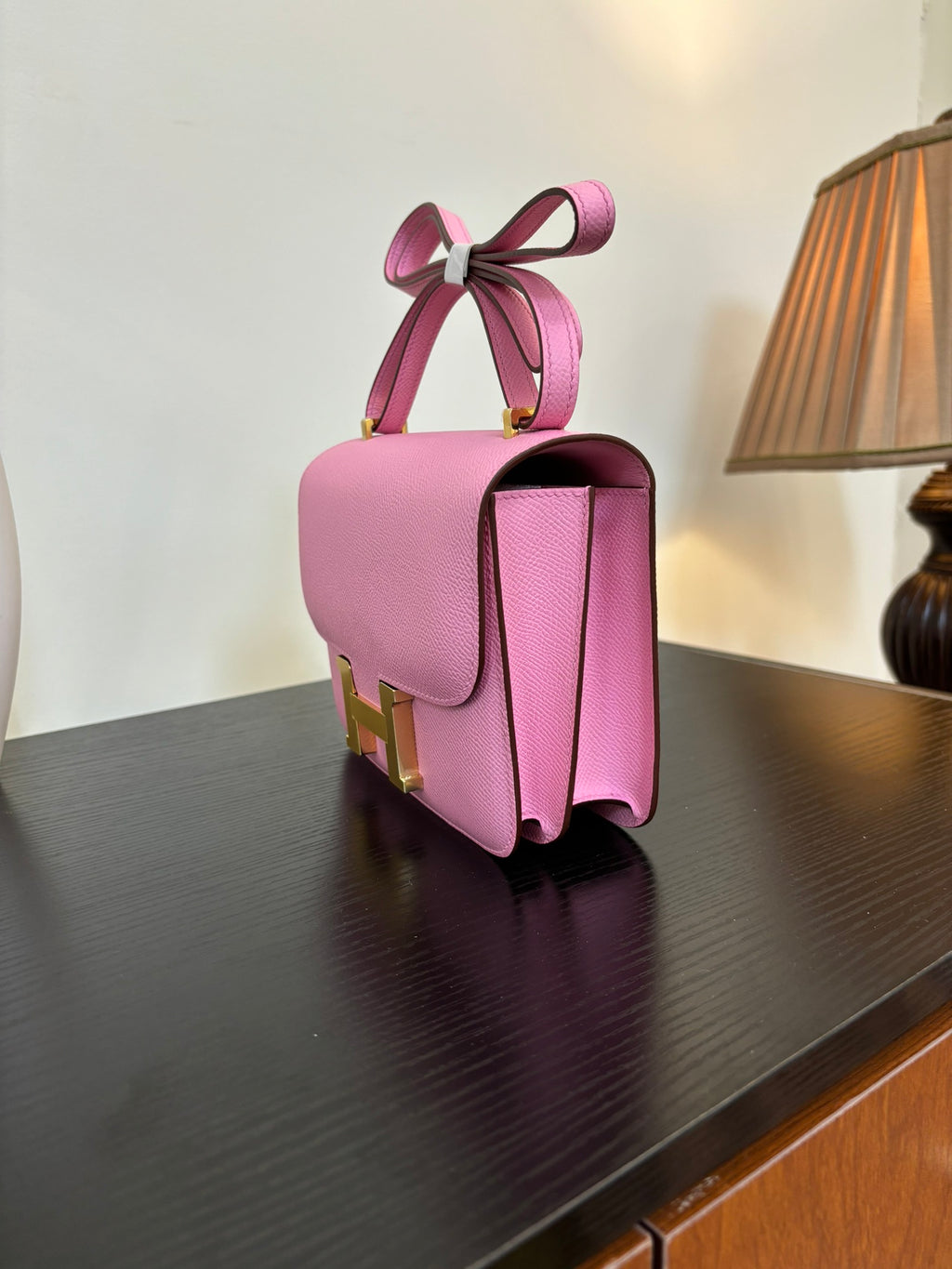Pink leather handbag with structured top handle and gold H clasp, side view