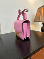 Pink leather handbag with structured top handle and gold H clasp, side view
