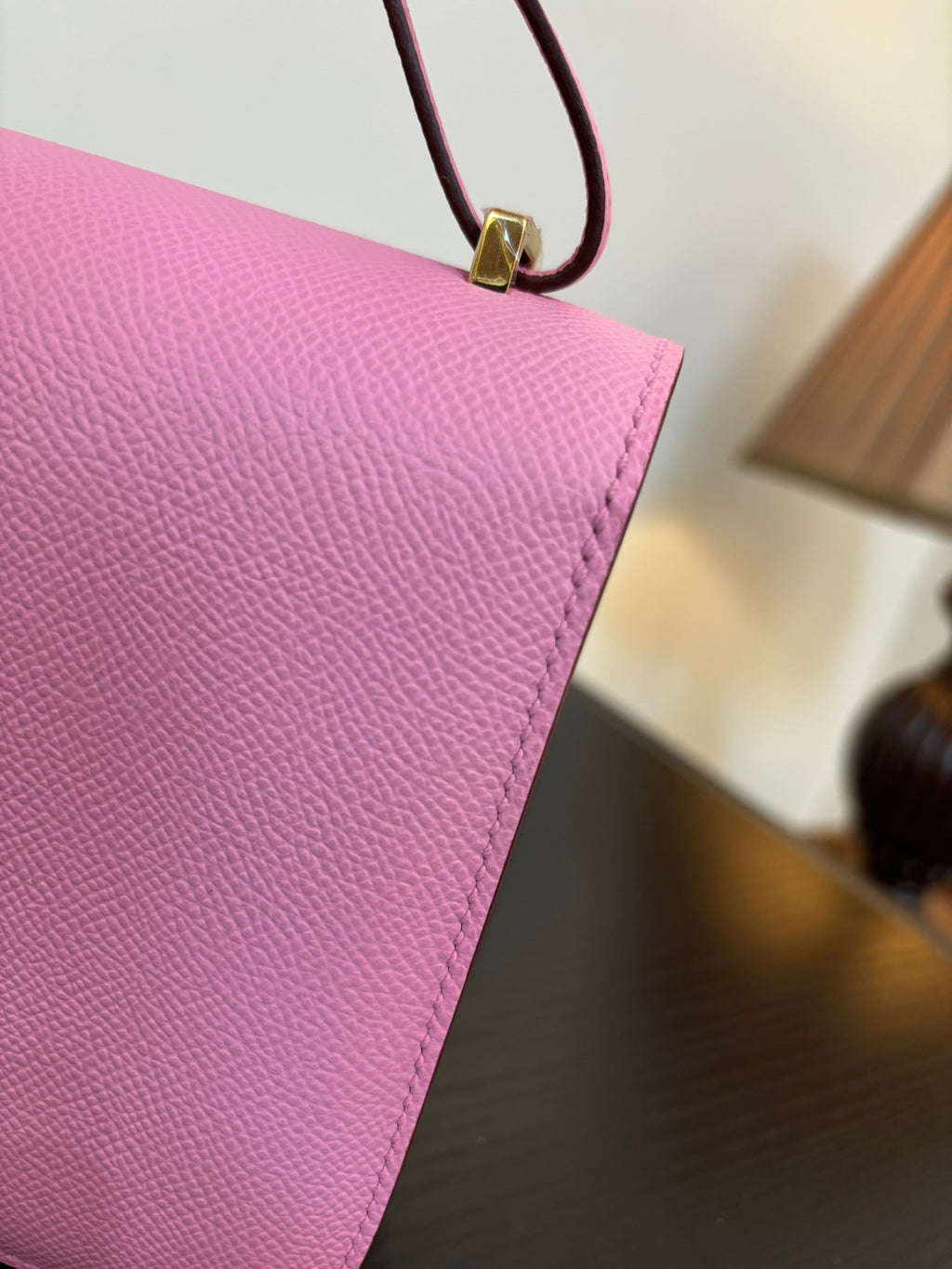 Pink textured leather handbag corner with attached strap and gold hardware