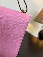 Pink textured leather handbag corner with attached strap and gold hardware