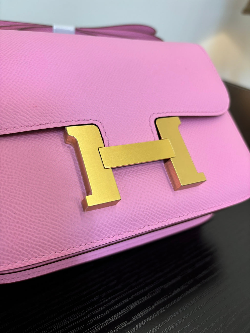 Pink leather handbag front flap with gold H clasp, close-up view