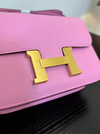 Pink leather handbag front flap with gold H clasp, close-up view