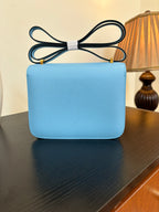 Hermes H bag light blue with flap front and gold H clasp; straight top handle view