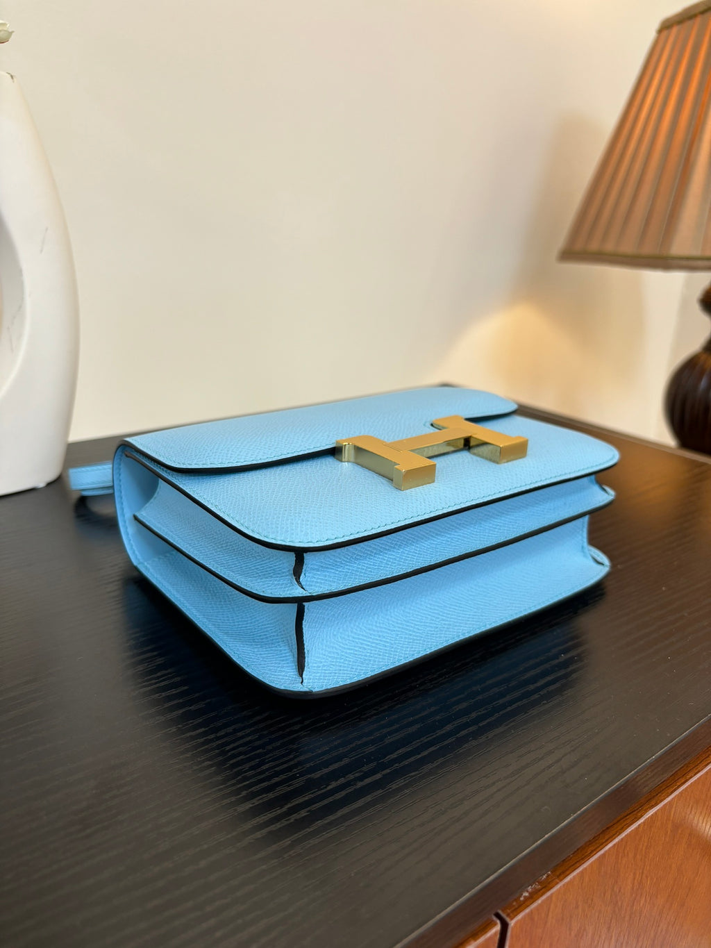 Hermes H bag light blue with gold H clasp on front, shown folded with handle cords