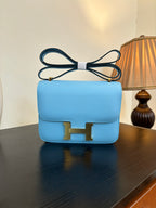 Hermes H bag light blue with flap front and gold H clasp; top handle strap
