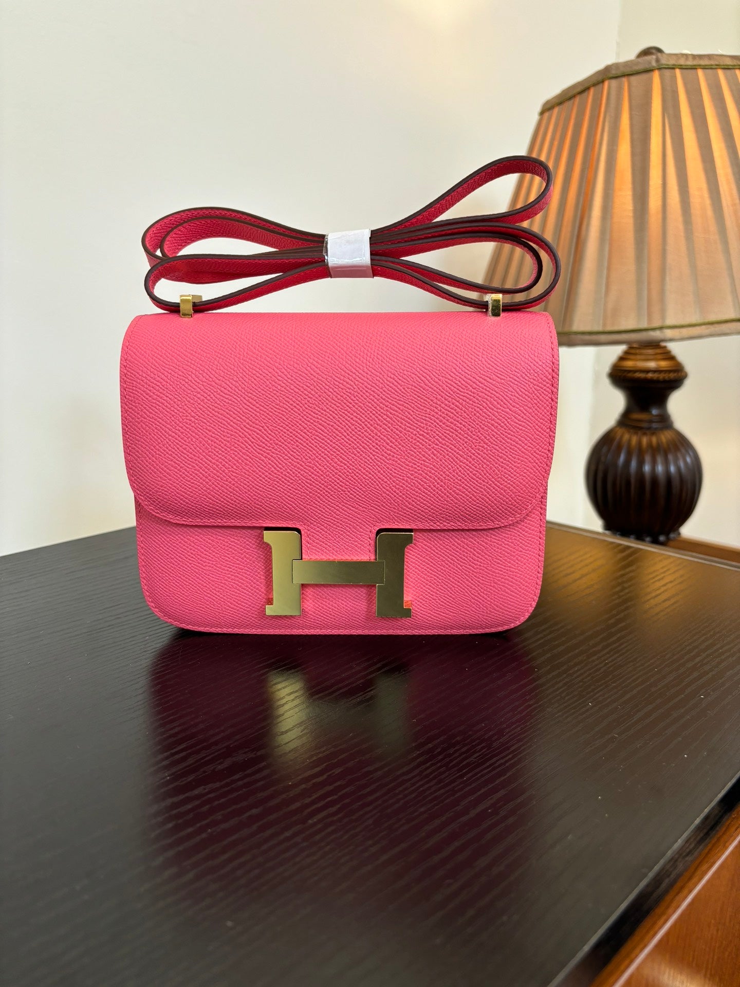Hermes pink mini flap bag with gold H front clasp and red shoulder strap.