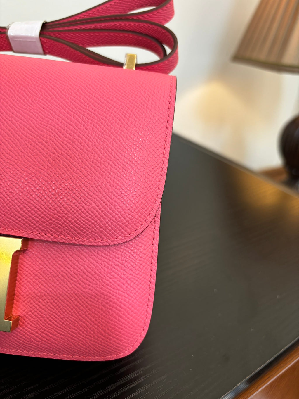 Hermes pink mini bag close-up of flap and textured leather with red strap hardware.