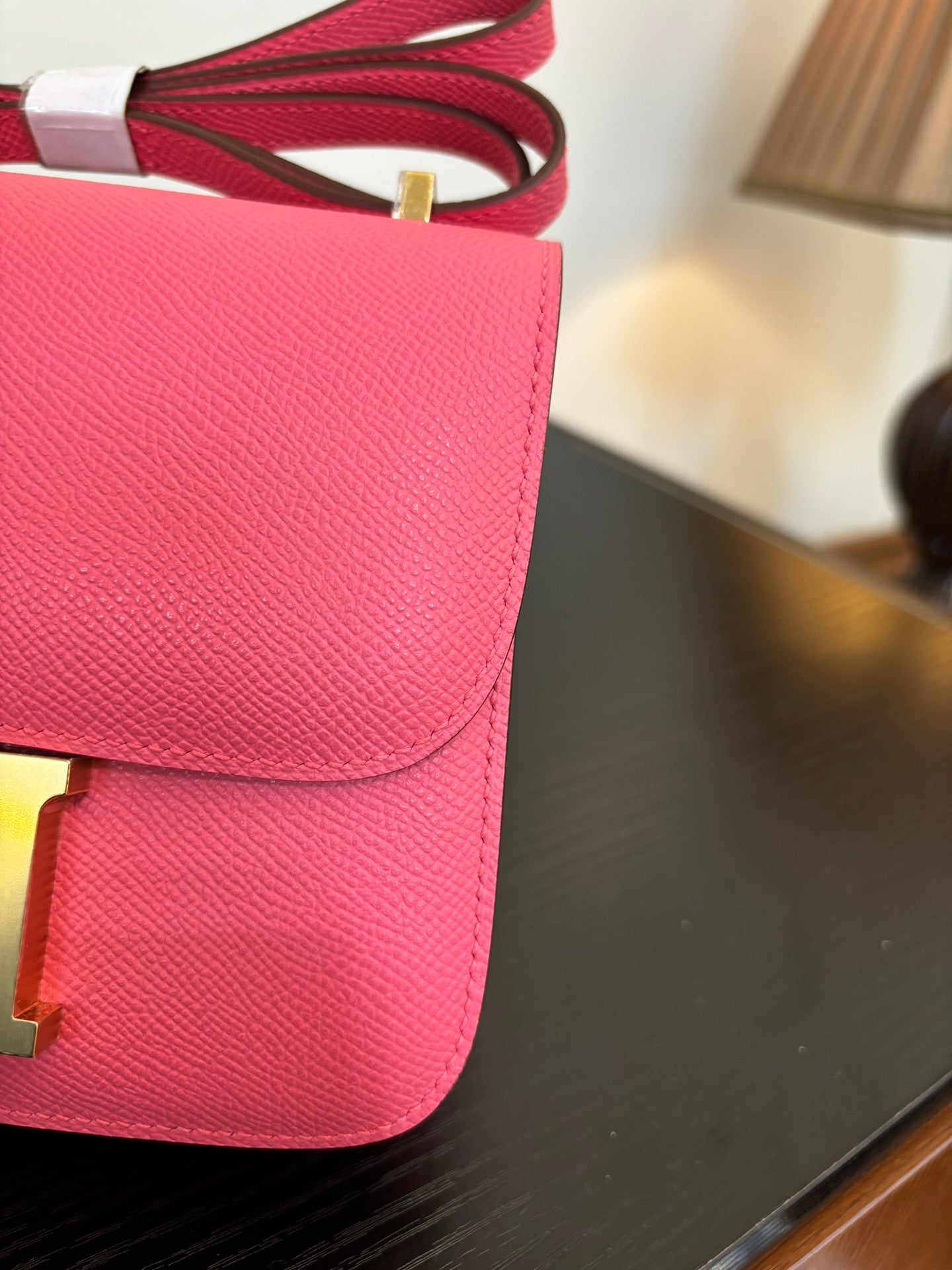 Hermes pink mini bag close-up of flap and textured leather with red strap hardware.