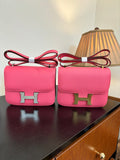 Hermes pink mini bag with flap and gold H clasp, red crossbody strap.