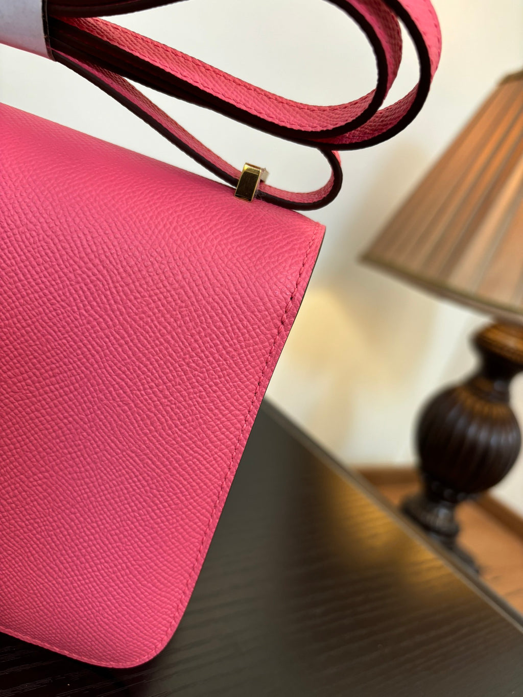 Hermes pink mini bag close-up of textured leather with red strap and metal buckle.