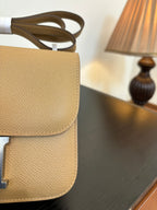 Beige leather-look bag back view with stacked flap and strap loop
