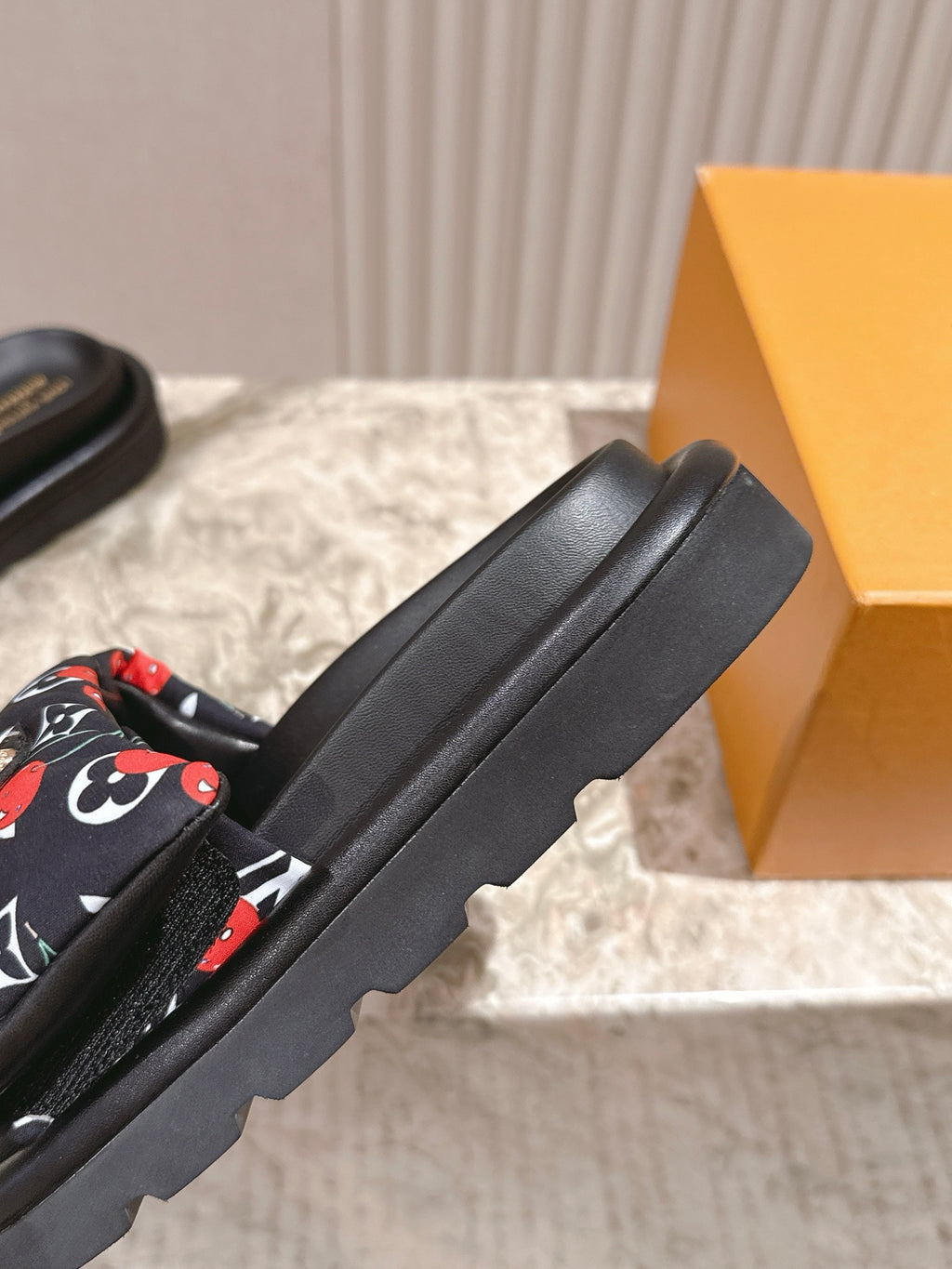 Louis Vuitton slide sandals showing black strap and thick platform sole.