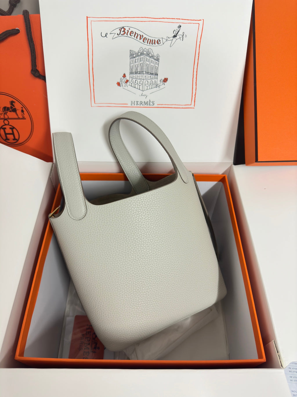 Hermes pale gray leather tote bag in box, front view with handle cutouts