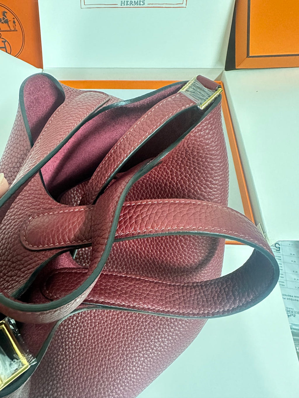 Burgundy textured leather bag with shoulder strap and gold-tone hardware