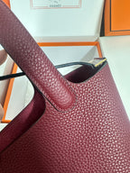 Burgundy textured leather tote handle close-up with gold-tone hardware at top