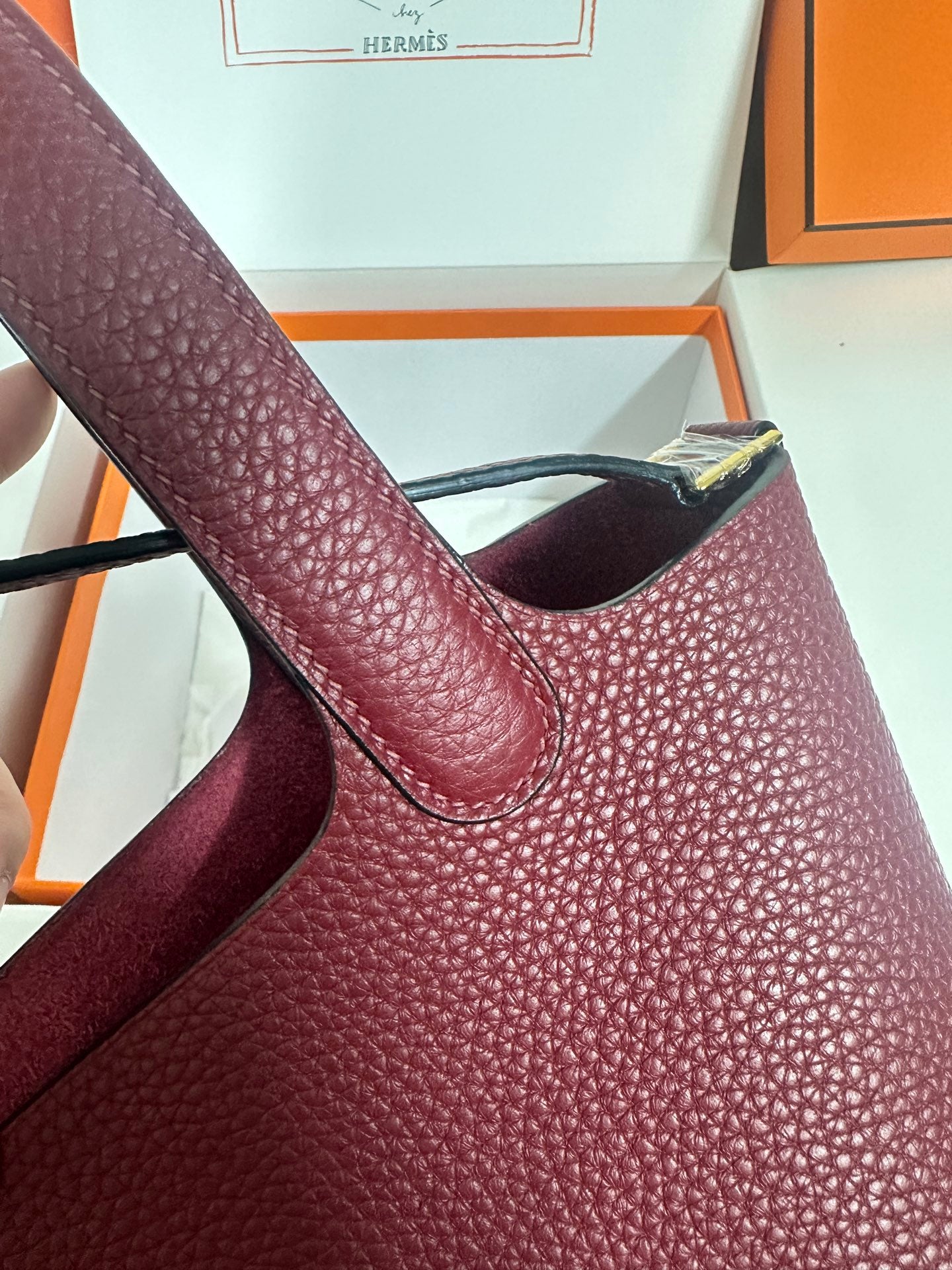 Burgundy textured leather tote handle close-up with gold-tone hardware at top