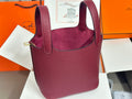 Burgundy textured leather tote bag with top handles and gold-tone hardware