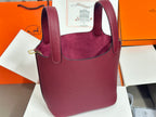 Burgundy textured leather tote bag with top handles and gold-tone hardware